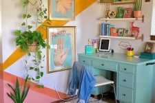 a maximalist home office with a color block accent wall, a turquoise desk, floating shelves, colorful art and lots of potted plants