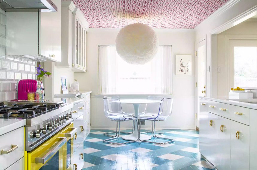 a maximalist kitchen with a bold blue printed floor, a bright yellow cooker, a colorful ceiling and a fluffy pedant lamp is a fun space