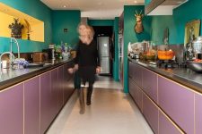 a maximalist kitchen with green walls and a hood and purple lower cabinets, a yellow niche and taxidermy