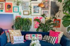 a maximalist living room with a large and bold gallery wall, with a bold blue sofa, statement plants and a brass lamp and a tray