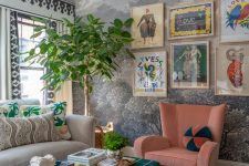 a maximalist living room with a wall mural, a grey sofa and a pink chair, a plaid ottoman, a bodl gallery wall and quirky textiles