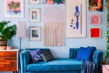 a maximalist living room with blue walls, a bold gallery wall, a bold blue sofa and an ottoman, a colorful gallery wall and a cool chandelier