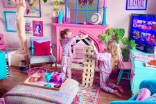 a maximalist living room with light pink walls, a hot pink fireplace, blue furniture and colorful textiles, a pink chandelier and a colorful gallery wall