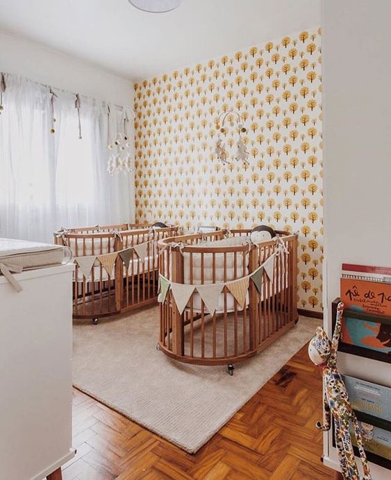 a mid-century modern nursery with an accent wall, matching cribs and buntings, a changing table and matching mobiles