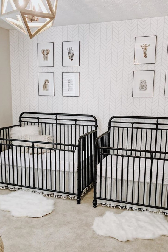 a mid-century modern nursery with an accent wallpaper wall, black metal cribs, a geometric lamp and layered rugs