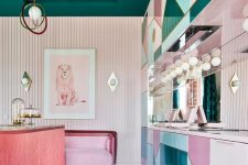 a refined maximalist kitchen with geometric pink, blush and blue cabinets, a pink kitchen island, a pink sofa and a dark green ceiling