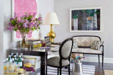 a sophisticated home office with a black desk and animal printed textiles, a striped rug, bold artworks and a gold bar cart is chic