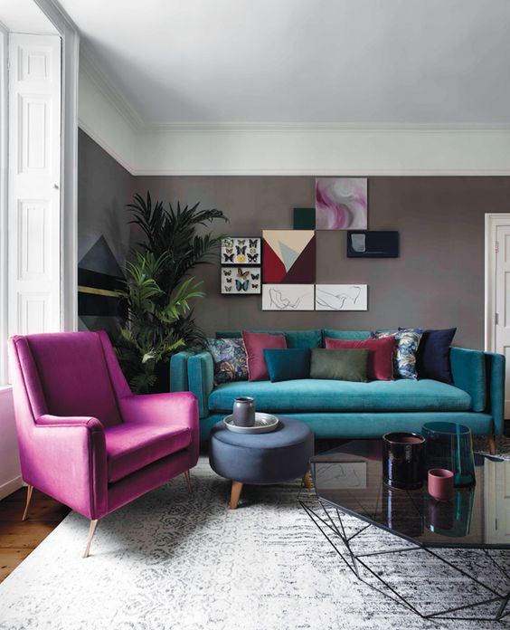 a stylish living room with grey walls, a turquoise sofa and a hot pink chair, a colorful gallery wall and a statement plant