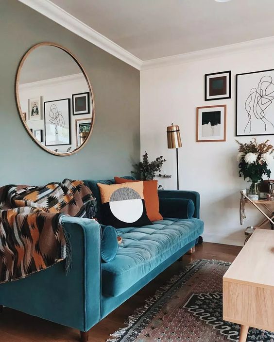 a stylish mid-century modern living room with a grey accent wall, a turquoise sofa, printed textiles and a monochromatic gallery wall