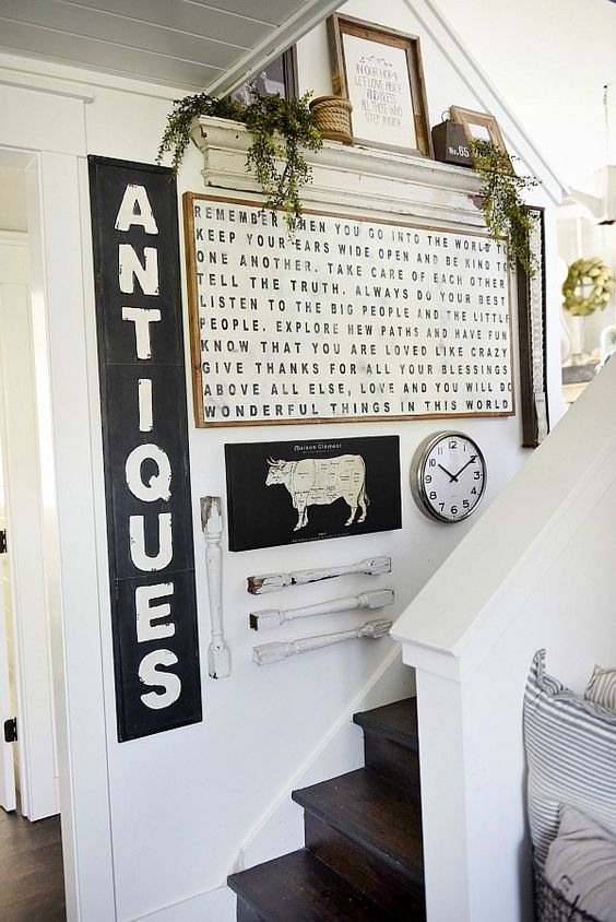 a vintage rustic gallery wall with signs in frames, railing pieces, greenery, rope and some signs on the shelf