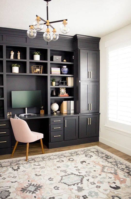 a modern farmhouse home office done with black kitchen cabinets, a blush chair, a retro chandelier and gold touches