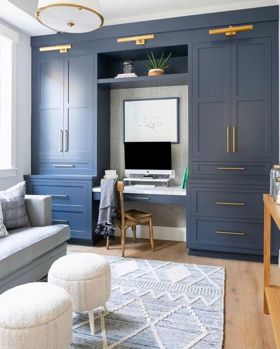 a stylish home office done with navy kitchen cabinets, a pastel blue sofa and faux fur stools, gold touches for more elegance