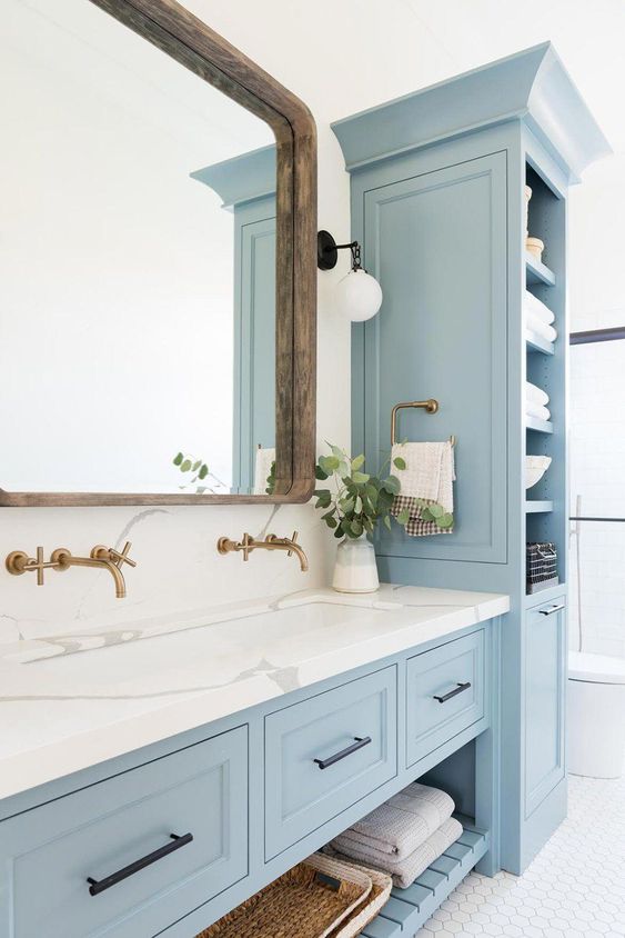 a lovely coastal bathroom done with light blue kitchen cabinets and a vanity that matches, with a white stone countertop