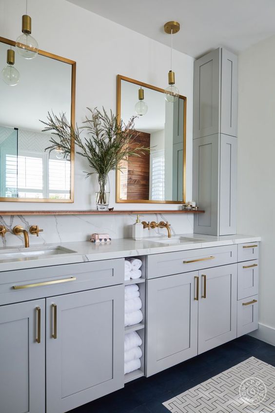 a light grey bathroom done with kitchen cabinets, a white stone countertop and a backsplash, a double sink and mirrror is super chic