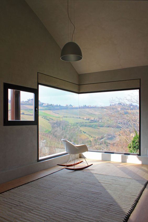a minimalist room with a large corner window with a fantastic view, a chair for sitting and enjoying this view and some tea here
