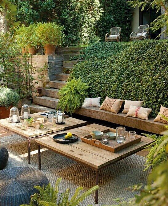 a beautiful and welcoming sunken terrace with greenery, built in benches and low tables plus poufs is an amazing outdoor space