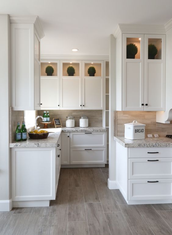 a chic modern French country kitchen in creamy shades, with grey stone countertops, lights and a tan tile backsplash is pure chic