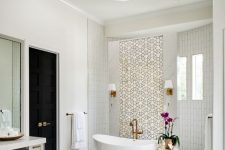 a fabulous fancy bathroom with white tiles and patterned ones, white marble tiles on the floor, a crystal chandelier and brass touches
