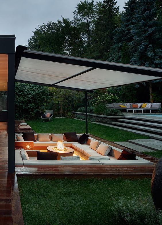 a lovely and welcoming contemporary conversation pit with a fire pit, built in upholstered benches and pillows around