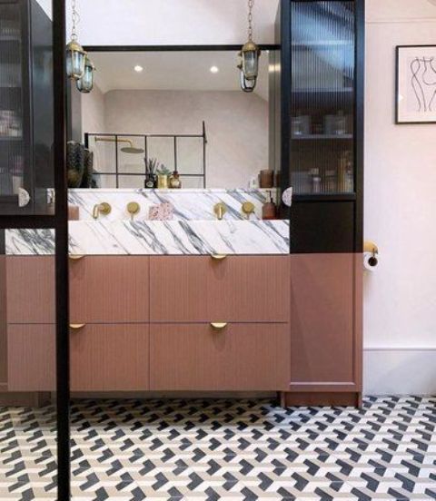 a luxurious bathroom with a geometric tile floor, a lovely vanity with a white marble countertop, gold touches and pendant lamps on chains