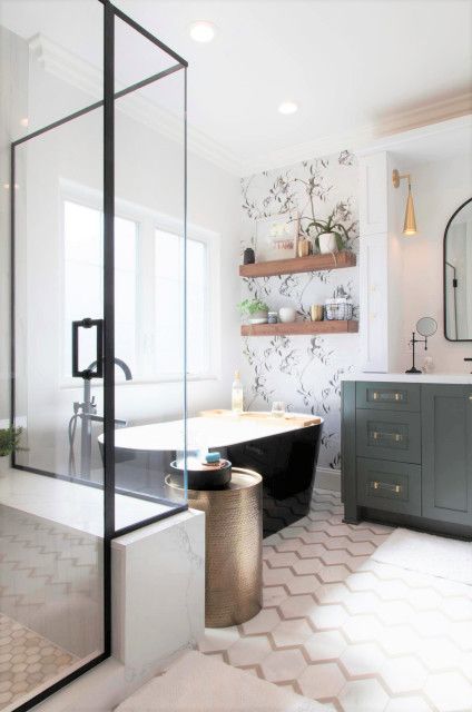 a modern country bathroom with a mosaic tile floor and a wallpaper accent wall, a shower and a black bathtub, a green vanity and potted plants