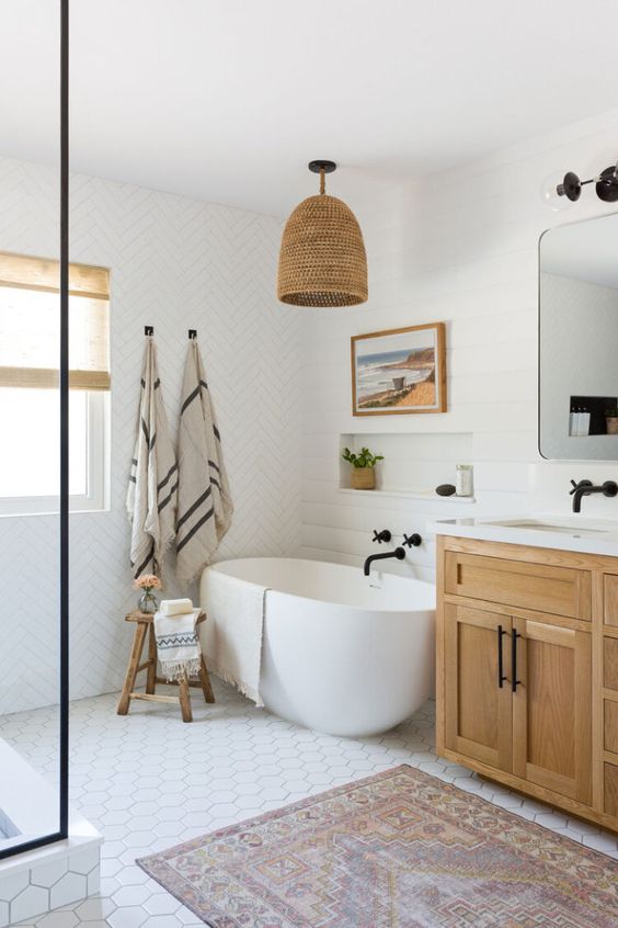 a modern country bathroom with white mismatching tiles, a stained vanity, white appliances, black fixtures and a woven lampshade