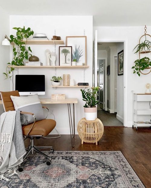 a modern country home office with floating shelves and a hairpin desk, a leather chair, a wooden stool and potted plants