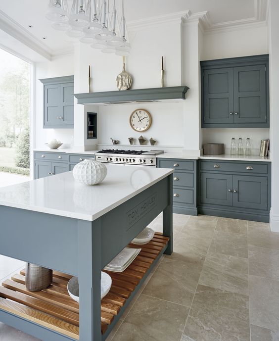 a modern country kitchen with graphite grey cabinets and a kitchen island, white countertops and a built-in hood plus a glazed wall