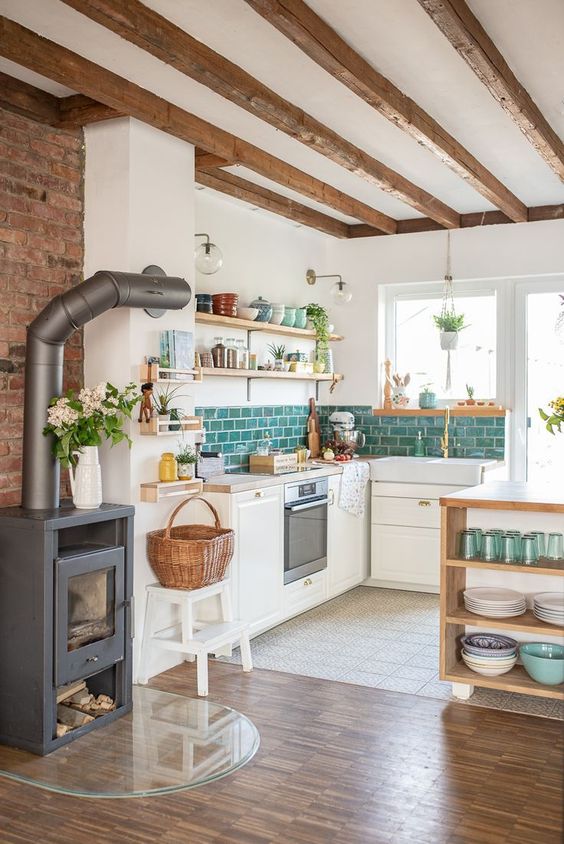 a modern country kitchen with white walls and white cabinetry, wooden beams on the ceiling, a hearth and a basket plus wooden shelves