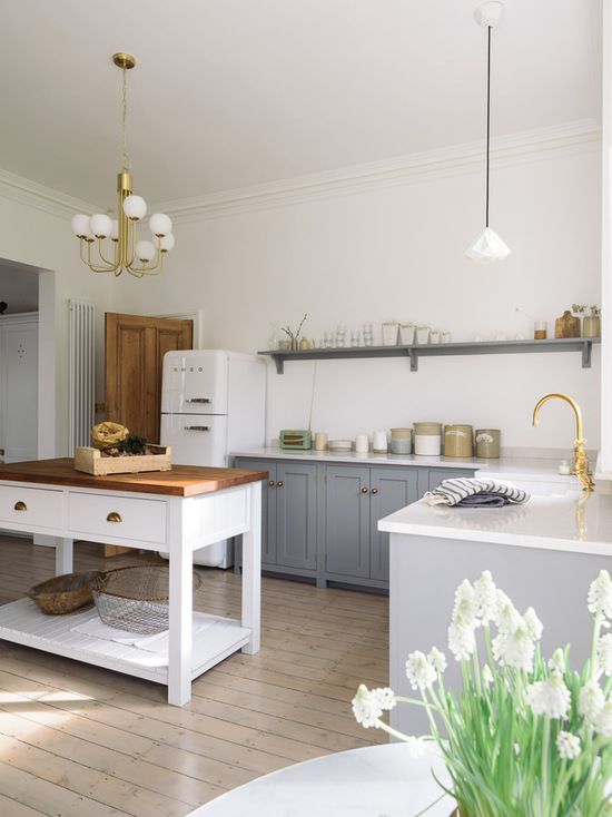 a modern country style kitchen with grey cabinets and a white kitchen island, pendant lamps and touches of gold