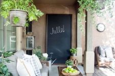 a modern country terrace with woven furniture, potted greenery, printed textiles and a chalkboard is a lovely and welcoming space