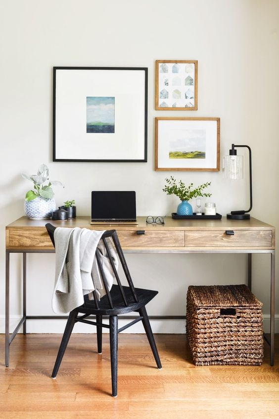 a modern country work station with a black vintage chair, a basket with a lid, a small gallery wall and some greenery