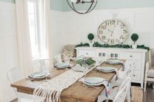 a modern farmhouse dining room with blue and white paneled walls, a stained vintage dining table, white metal chairs, a sphere chandelier
