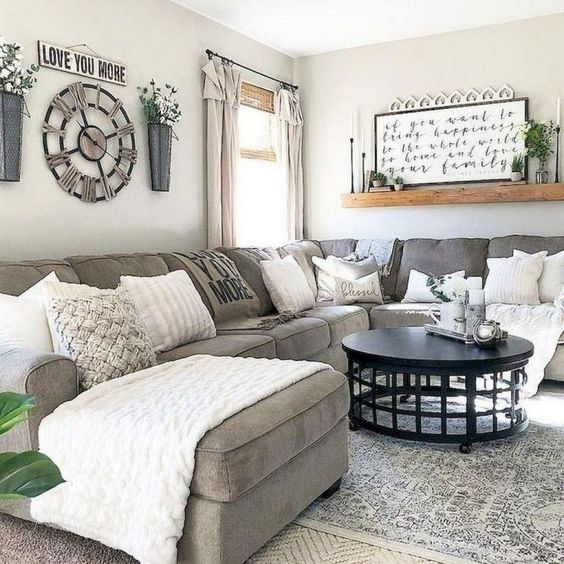 a modern farmhouse living room with a grey sectional, an open shelf, some wall decor and neutral and printed pillows