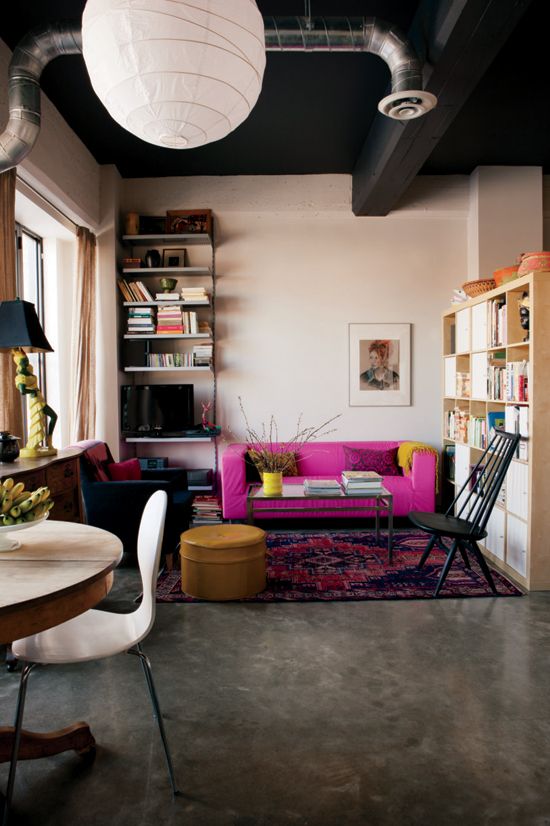 a moody apartment with an industrial feel, blush walls and a black ceiling, a hot pink sofa for a bold color statement
