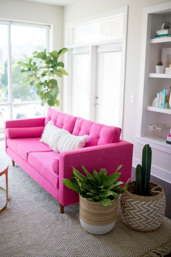 a neutral living room with a hot pink sofa for a color statement, potted plants in baskets and built-in storage units