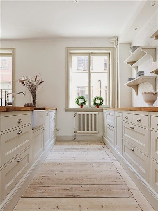 a neutral modern country kitchen with shaker style cabinets, butcherblock countertops and a wooden floor is a very cozy and welcoming space