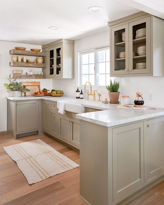 a welcoming dove grey modern country kitchen with shaker style cabinets, white marble countertops, a white tile backsplash and open shelves