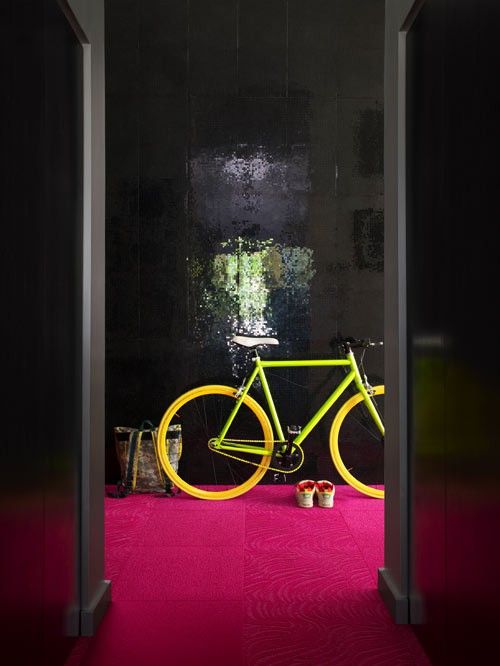 a whimsical entryway with glossy black walls, a hot pink floor, a neon green and yellow bike is amazing