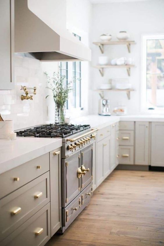 an elegant light grey modern country kitchen with white stone countertops, a vintage cooker and a chic hood plus open shelves