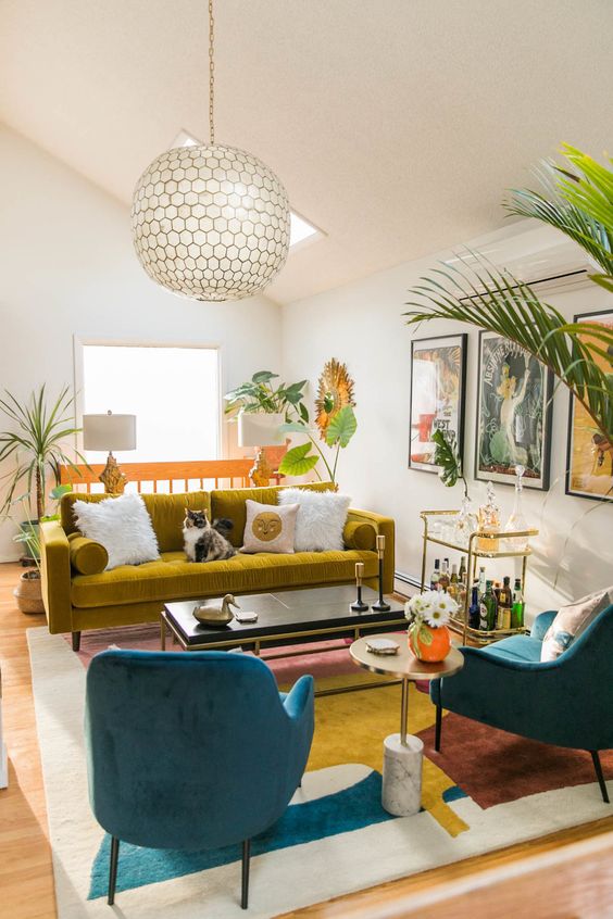 a vibrant living room in bold colors, with a mustard sofa, navy chairs, a bold abstract rug, potted plants and a cool bar cart