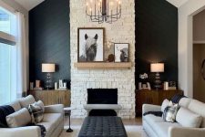 11 a chic living room wiht a black accent wall, a fireplace, grey sofas, black benches, a black ottoman and a vintage chandelier