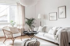 14 a neutral living room with a white sofa, a rattan chair, neutral textiles, potted greenery and a delicate gallery wall