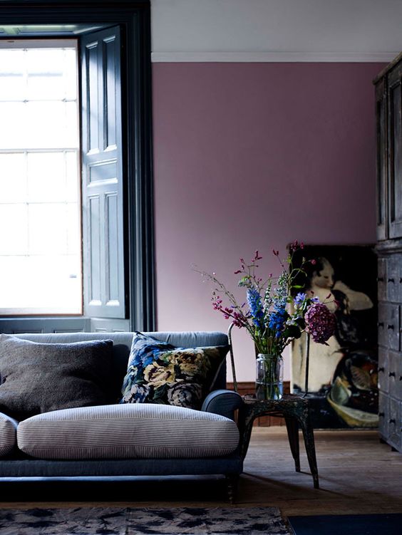 a beautiful living room with a purple accent wall, a navy and grey sofa, a pretty artwork and a vintage sideboard is a gorgeous space