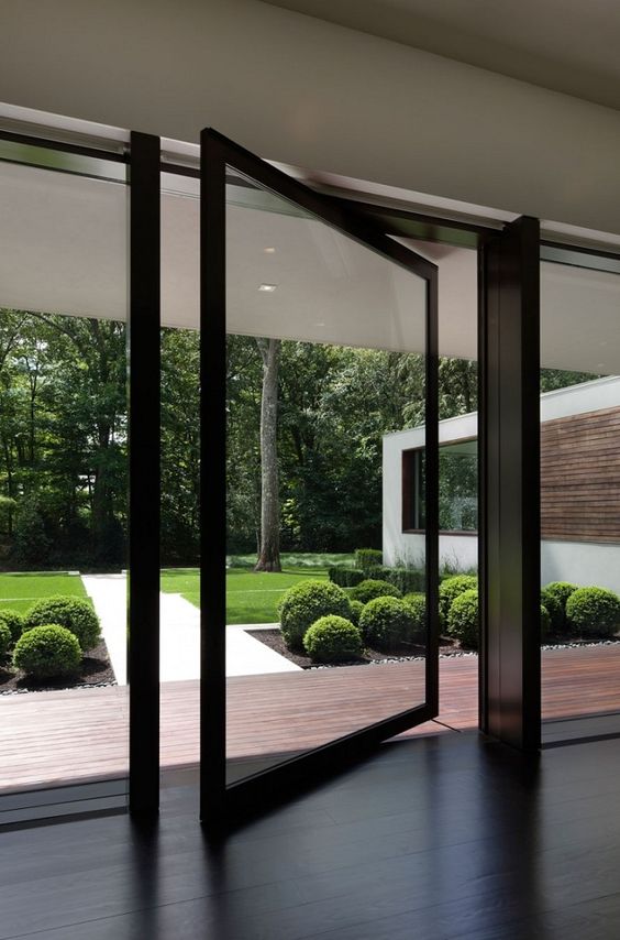 a black framed pivot glass door is a very ethereal and lightweight solution for a contemporary or minimalist home