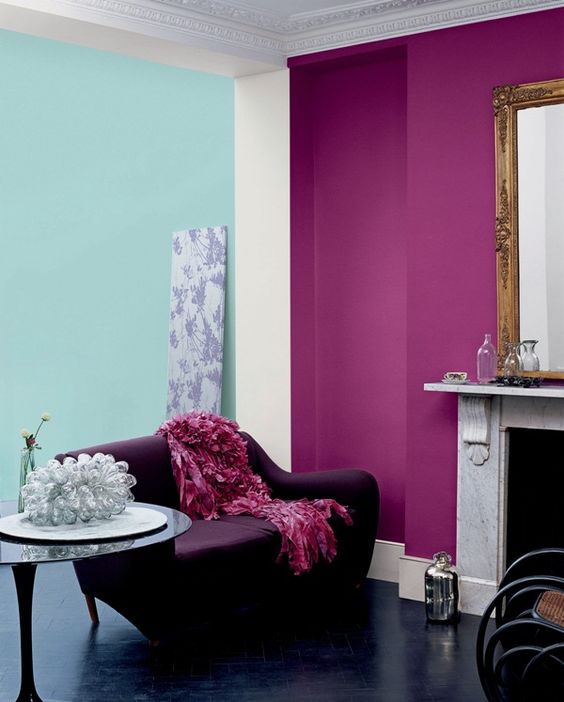 a bold and catchy living room with a purple accent wall, a fireplace clad with marble, a mirror in a vintage frame, a purple sofa and some pretty decor