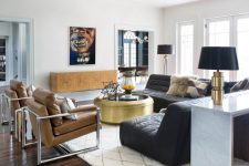a bold contemporary living room with a floating credenza, black sofas, tan leather chairs, a gilded coffee table and a statement artwork