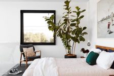 a chic bedroom with stained furniture, pastel bedding, a statement artwork and a statement potted plant is very welcoming