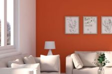 a chic modern living room with an orange accent wall that sets up the mood, neutral sofas, a cool table and a mini botanical gallery wall