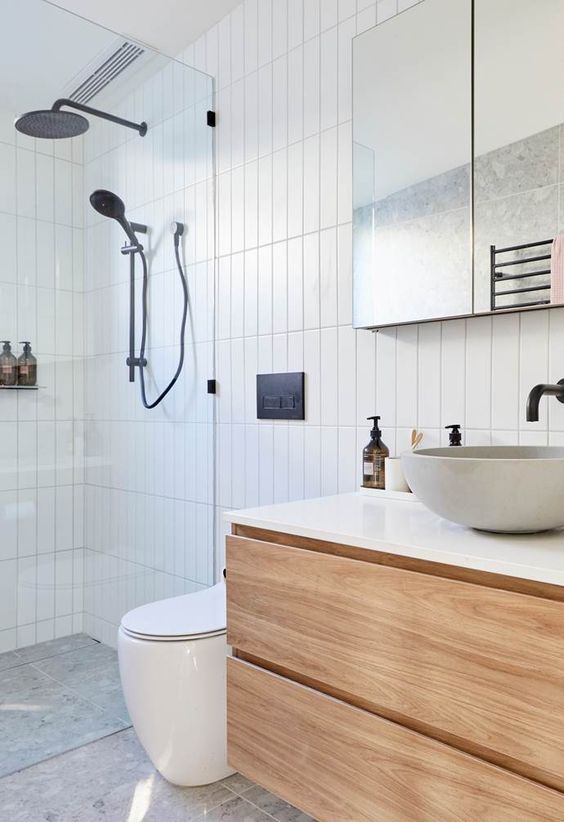 a contemporary bathroom clad with skinny tiles, with a floating vanity, a shower space, a mirror and black fixtures for a contrast